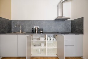 Eine Küche mit integriertem Spülbecken, einem Edelstahl-Dunstabzug und einer Arbeitsplatte mit Kaffeemaschine und Wasserkocher.