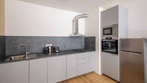 Una cocina moderna con un lavamanos de acero inoxidable, hervidor, tostadora, horno y refrigerador.