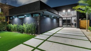 A modern building with a dark facade, numbered 243, and a well-lit entrance with a paved pathway. - 4BR Sleek, Art, Design District, Private Pool, Ping Pong & Grill (Miami)
