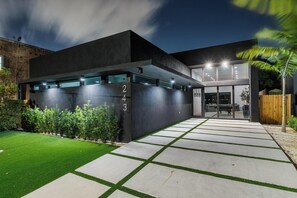 A modern building with a dark facade, numbered 243, and a well-lit entrance with a paved pathway. - 4BR Sleek, Art, Design District, Private Pool, Ping Pong & Grill (Miami)