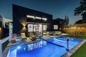 A modern house with a swimming pool, outdoor seating, and a basketball hoop. - 4BR Sleek, Art, Design District, Private Pool, Ping Pong & Grill (Miami)
