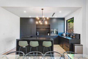A modern kitchen with a central island, bar stools, and a built-in oven. - 4BR Sleek, Art, Design District, Private Pool, Ping Pong & Grill (Miami)
