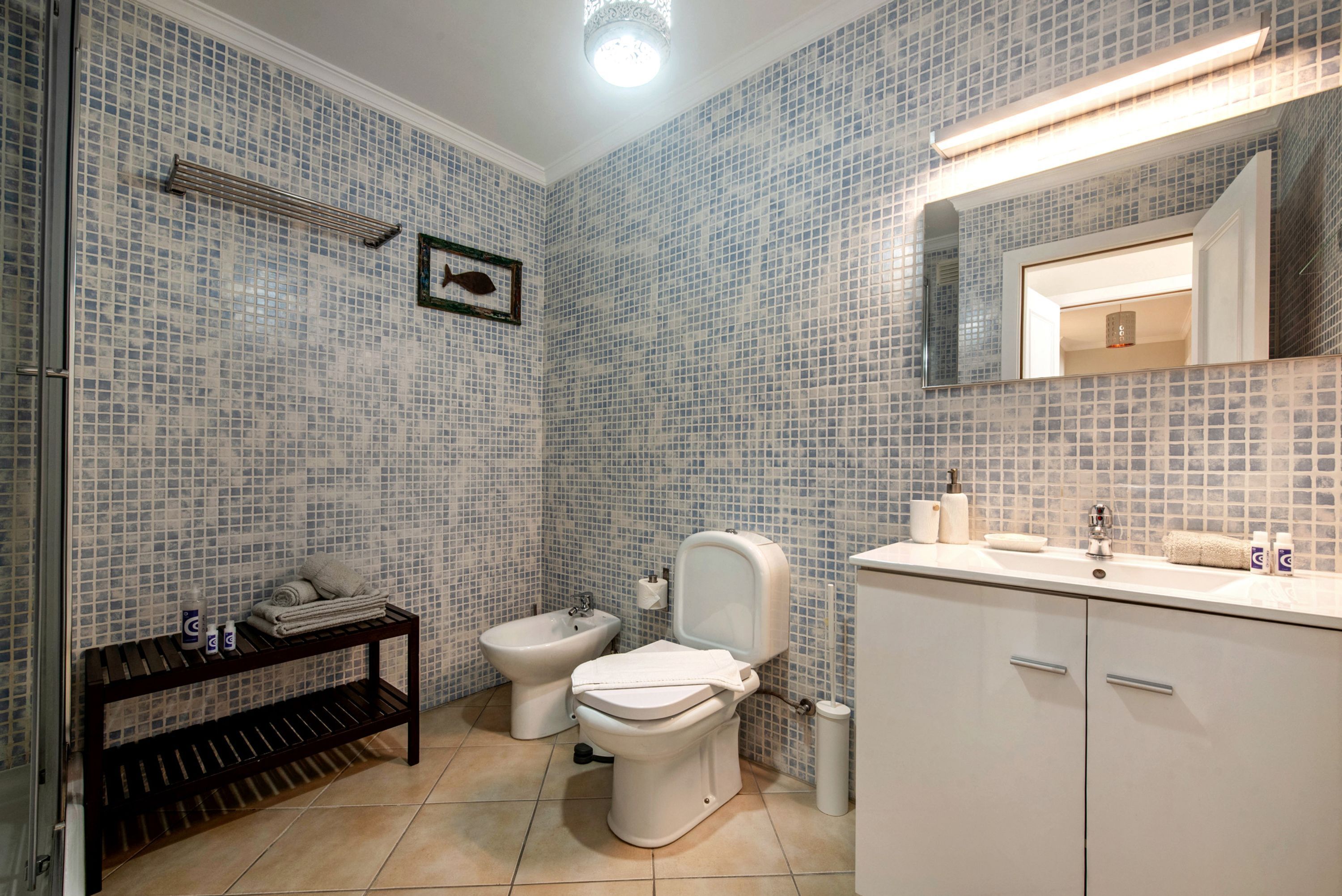 A bathroom with a toilet, bidet, sink, and a mirror.