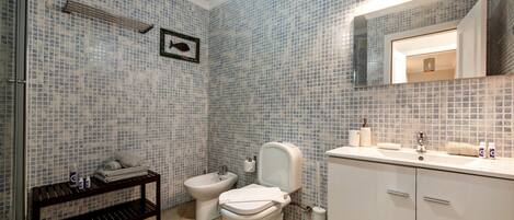 A bathroom with a toilet, bidet, sink, and a mirror.