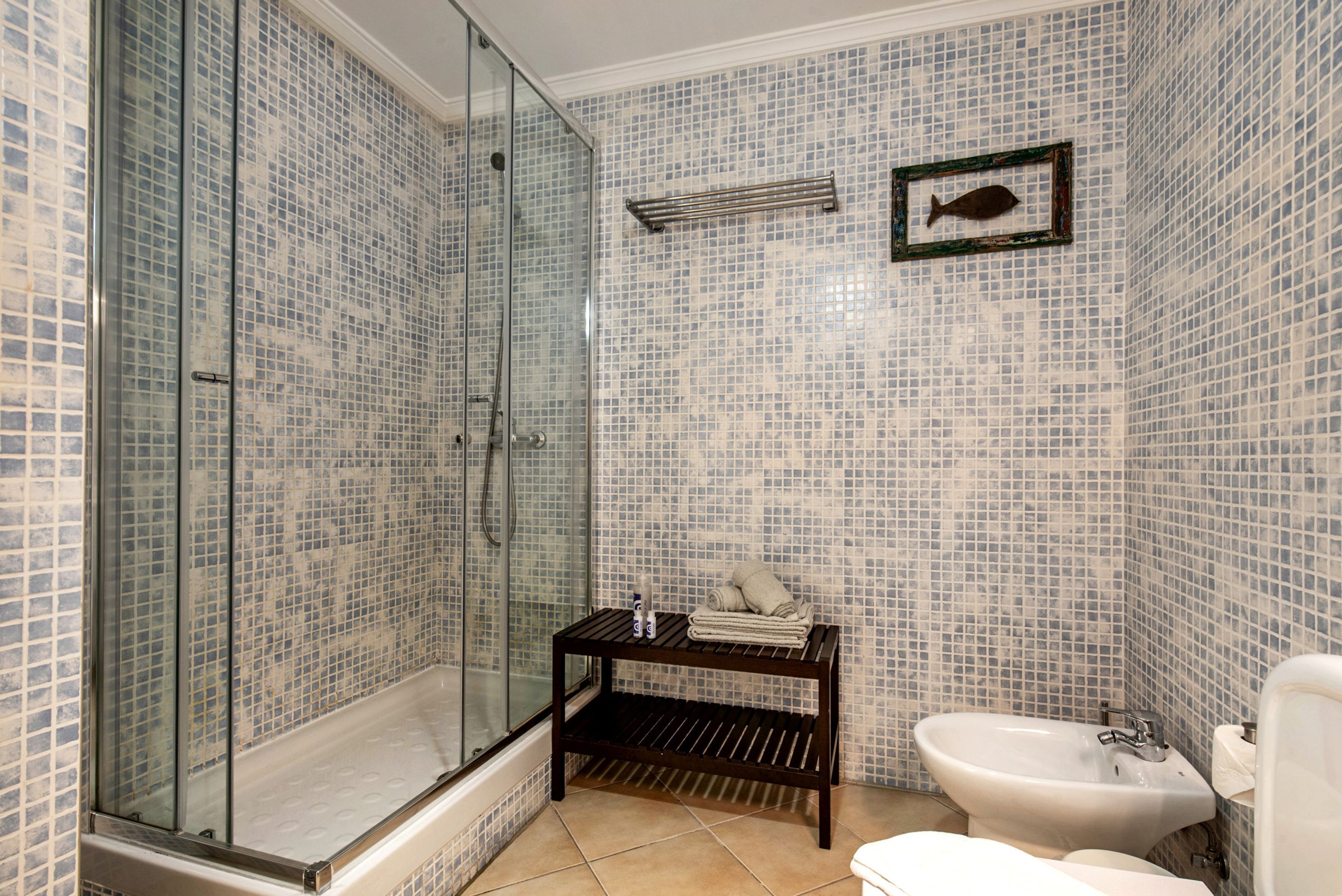 A bathroom with a glass-enclosed shower, a sink, and a toilet.