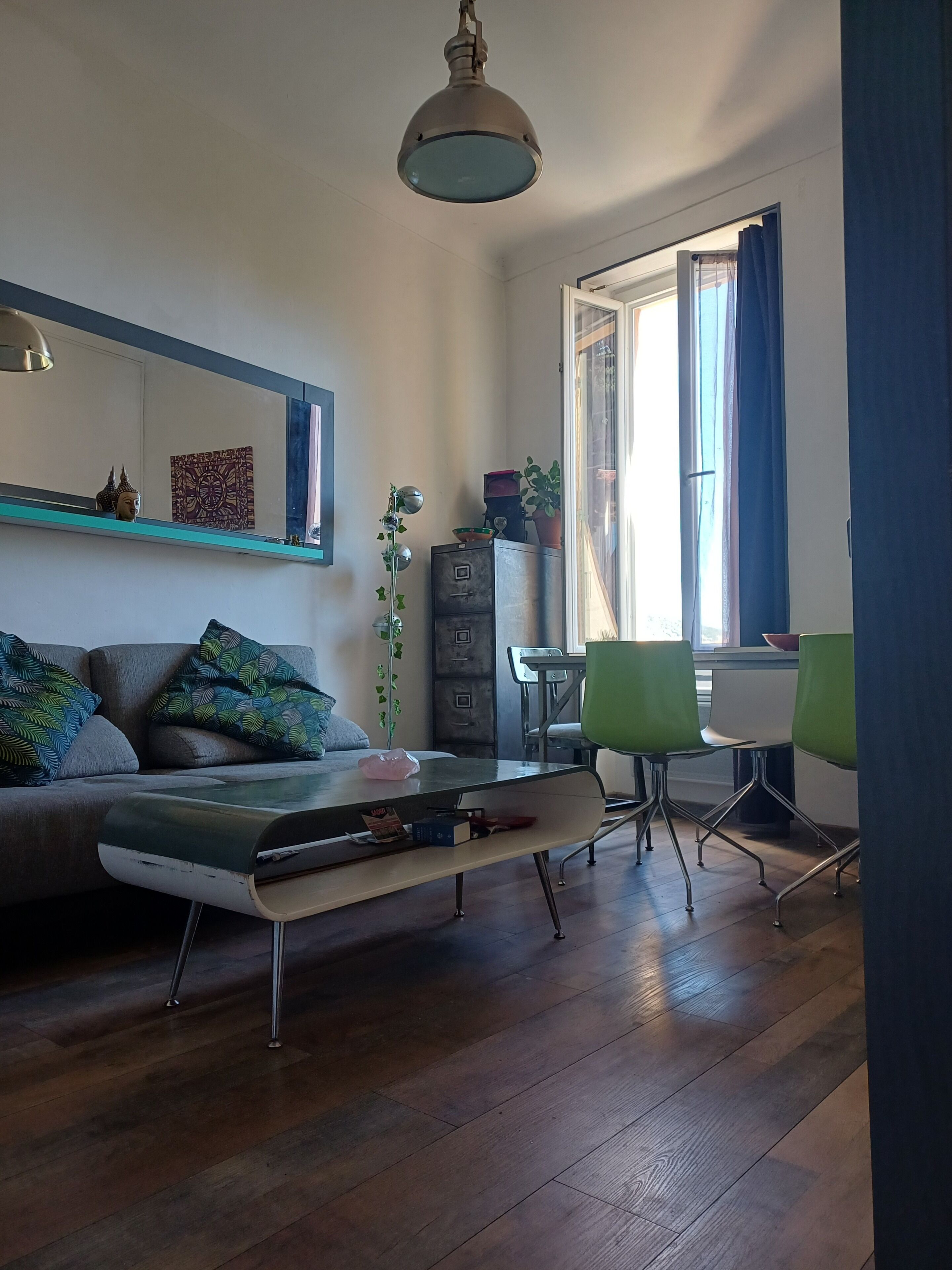 A living room with a sofa, a coffee table, a dining table with chairs, a potted plant, and a cabinet.