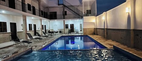 An indoor swimming pool with a clear view of the pool area, a staircase, and a balcony.