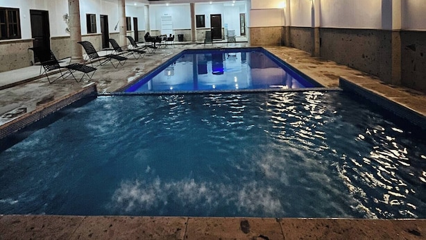 An indoor swimming pool with a clear view of the pool area, a staircase, and a balcony. - Nacho Apartments (Puerto Vallarta)