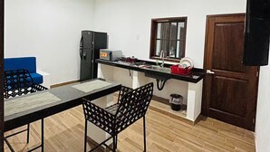 A compact kitchen with a dining area, a ceiling fan, and a wooden door. - Nacho Apartments (Puerto Vallarta)