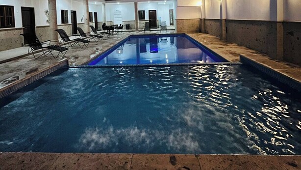 An indoor swimming pool with a clear view of the pool area, a staircase, and a balcony. - Nacho Apartments (Puerto Vallarta)