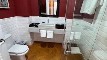 A bathroom with a white toilet, a sink with a mirror above it, and a glass-enclosed shower area.