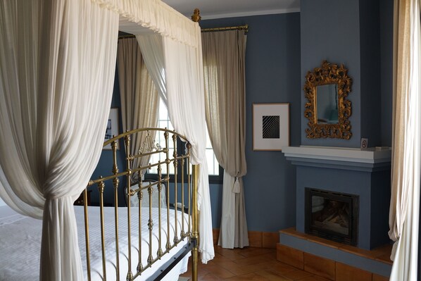 Ein Schlafzimmer mit Himmelbett, Kamin und Spiegel an der Wand.