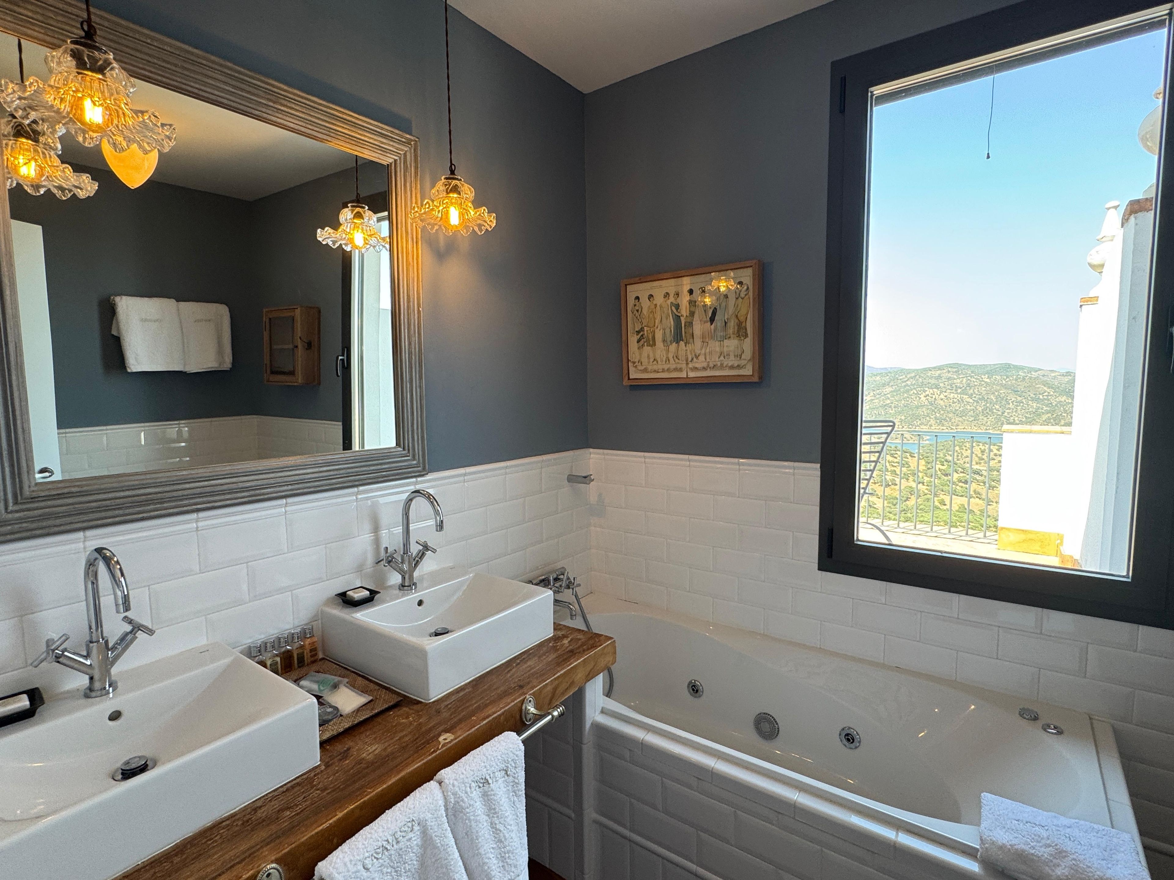 Un baño con dos lavamanos, una bañera, un espejo grande y una ventana con vistas.