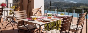 An outdoor dining area with a table set for two, chairs, and a view of a lake. - Casa Vesta (Zufre)