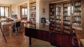 Una biblioteca con estanterías, un escritorio, un piano y un telescopio.