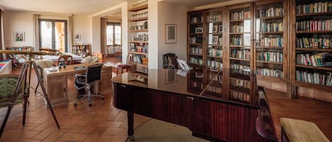 A library with bookshelves, a desk, a piano, and a telescope.