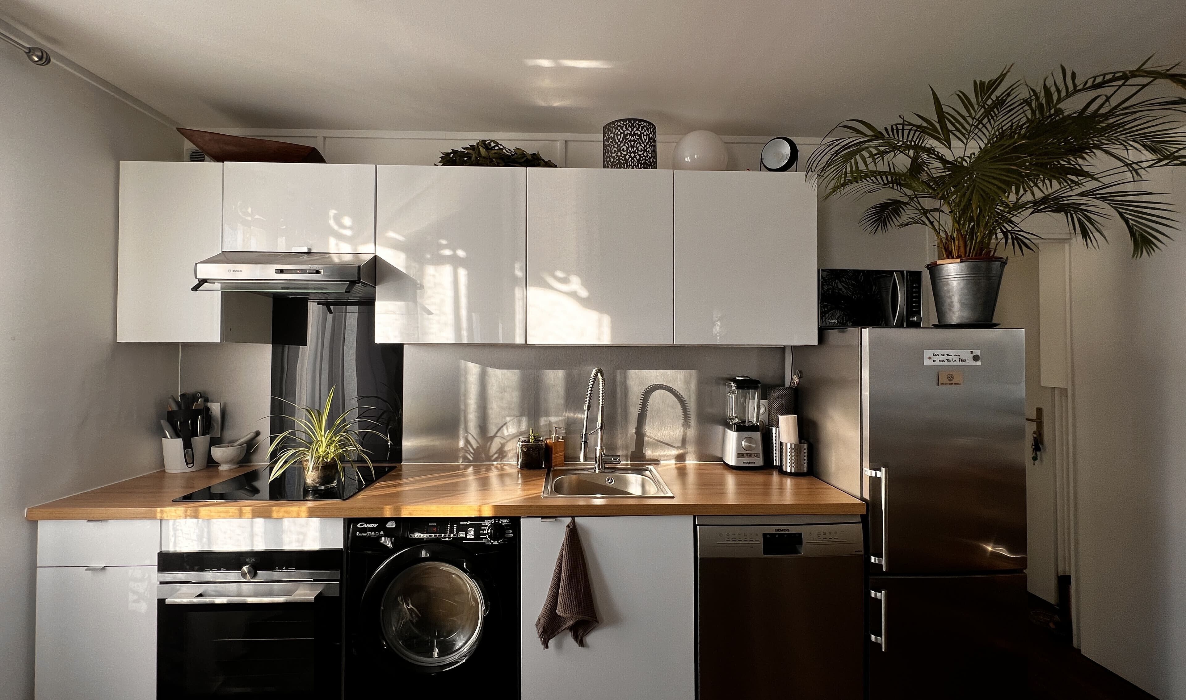 Une cuisine compacte équipée d’un lave-linge, d’un lave-vaisselle et d’un four encastré.