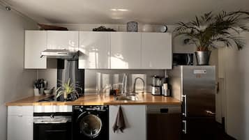 Une cuisine compacte équipée d’un lave-linge, d’un lave-vaisselle et d’un four encastré.