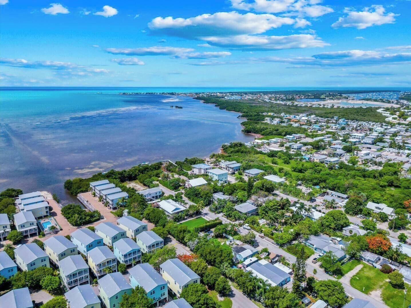 A coastal residential area with houses, a beach, and a clear sky.