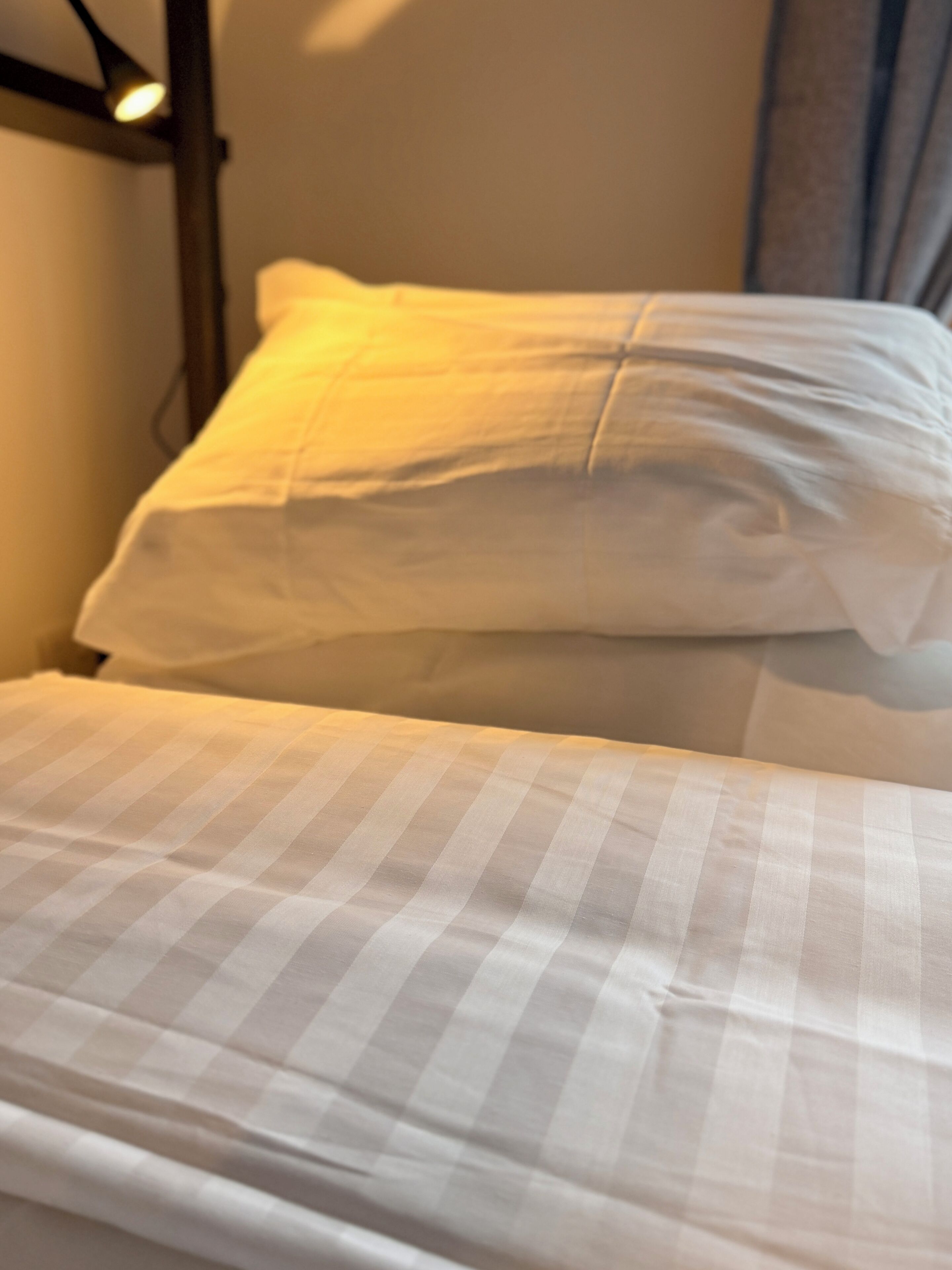 A bed with a checkered bedspread and a white pillow.