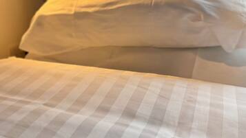 A bed with a checkered bedspread and a white pillow.