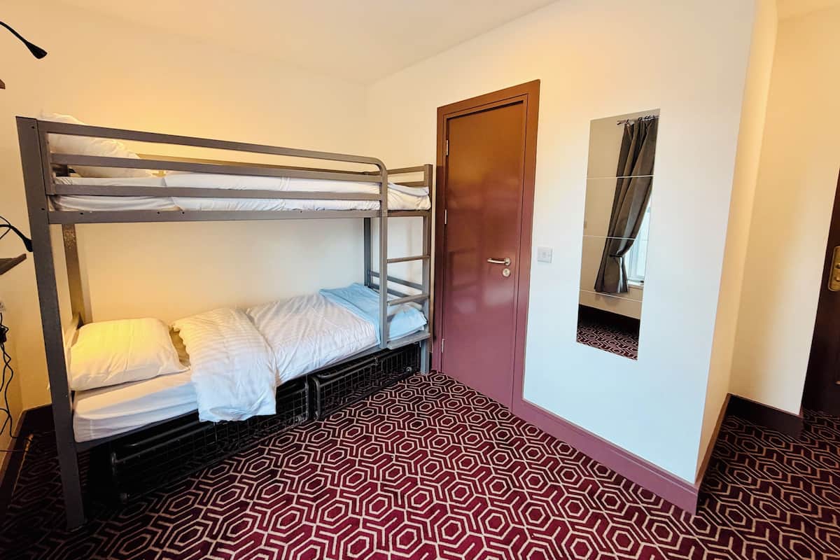 A bunk bed room with a door, a patterned floor, and a light fixture.