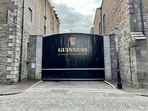 Una reja de metal negro con el logotipo de Guinness y el texto 'St. James's Gate Brewery, Dublin' en un edificio de ladrillo.