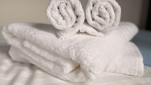 A stack of white towels with a rolled towel on top.