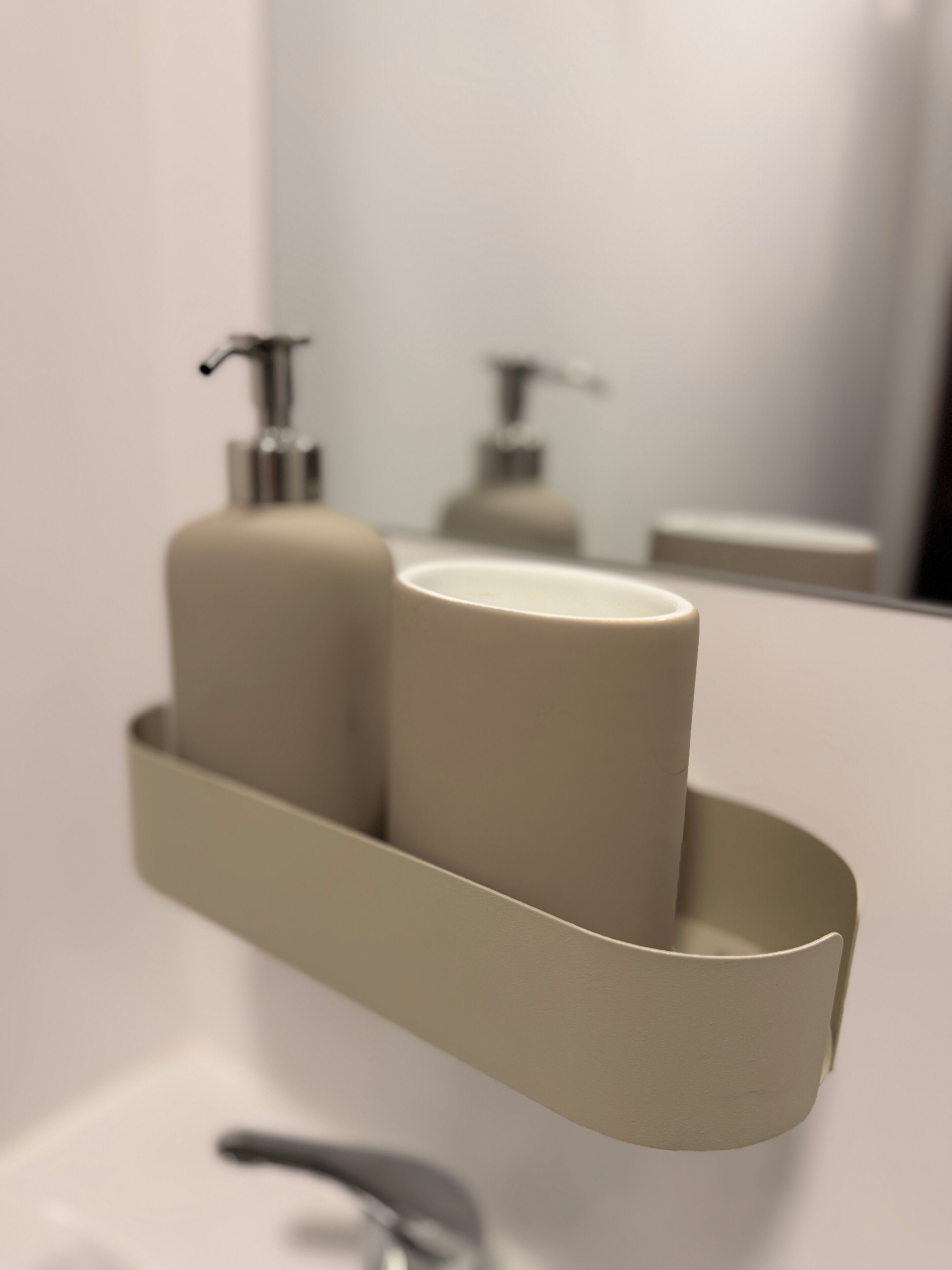 A bathroom with a sink, a mirror, and a shelf with two toiletries.