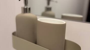 A bathroom with a sink, a mirror, and a shelf with two toiletries.