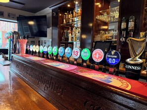A bar with a row of beer taps, a Guinness tap, and a harp decoration. - Coopers Lane (Dublin)