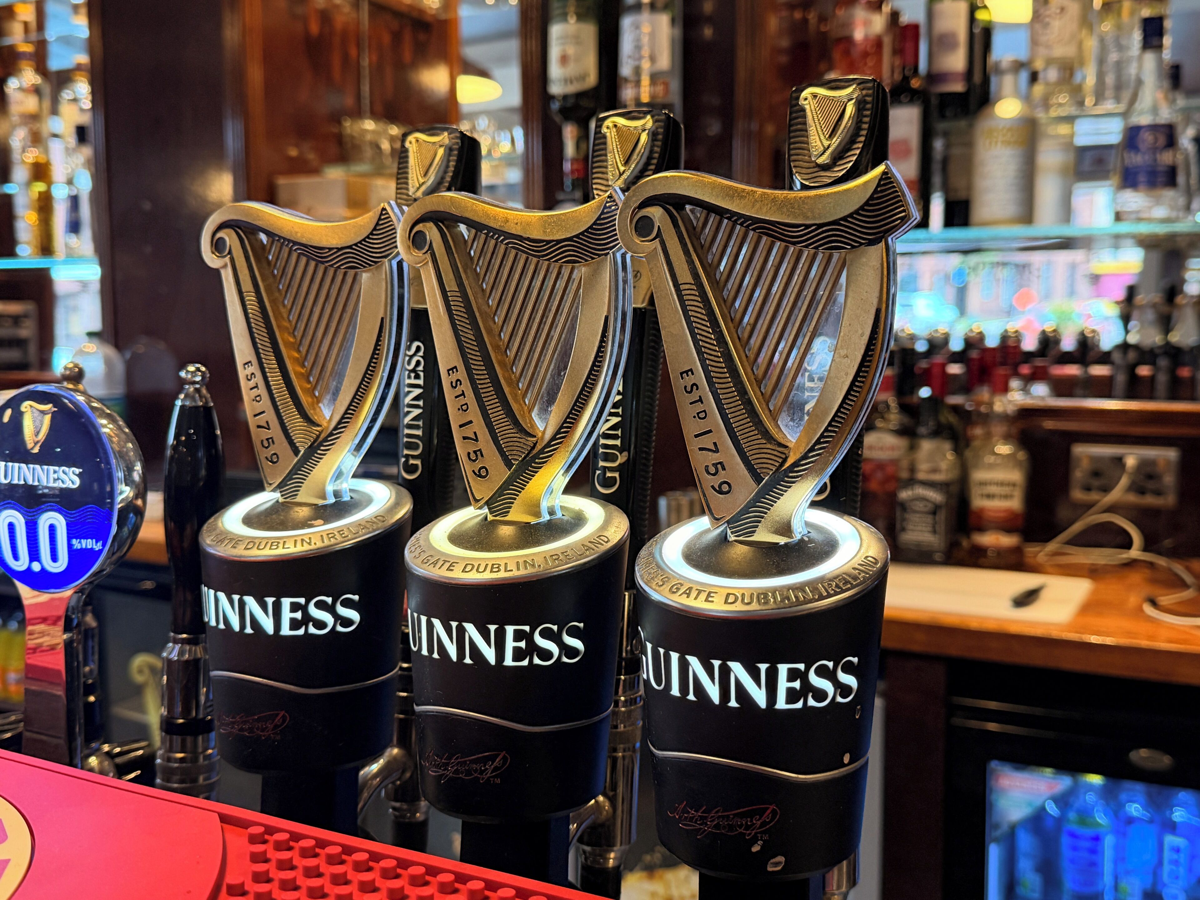 Three Guinness beer taps with a harp logo, placed on a bar counter.