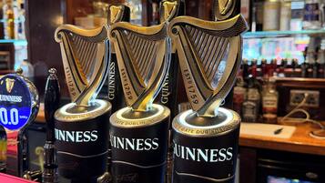 Three Guinness beer taps with a harp logo, placed on a bar counter.