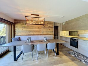 Una cocina moderna con horno integrado y una zona de comedor con mesa y sillas.