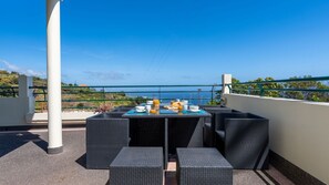 A terrace with a table set for breakfast, overlooking a scenic view. - Desertas Vista Casa by LovelyStay (Gaula)
