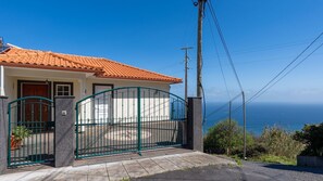 A house with a red-tiled roof, a gated entrance, and a view of the ocean. - Desertas Vista Casa by LovelyStay (Gaula)