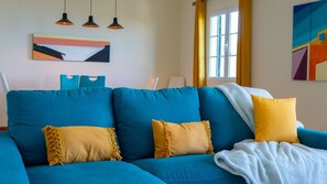A blue sofa with yellow pillows, a white blanket, and a painting on the wall. - Desertas Vista Casa by LovelyStay (Gaula)