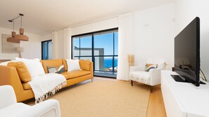 Ein modernes Wohnzimmer mit einer Couch, einem Sessel und einem Flachbildfernseher.