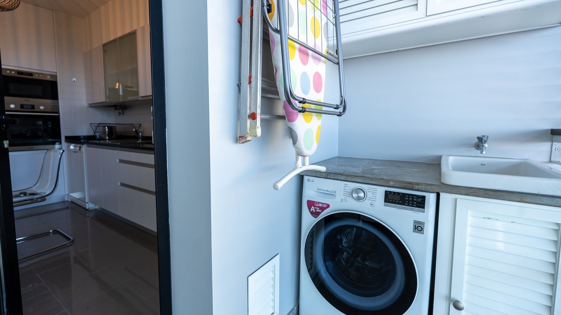 A compact kitchen with a washing machine, a sink, and a microwave.