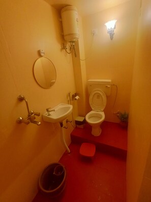 Un bagno compatto con il water, il lavandino e uno specchio.