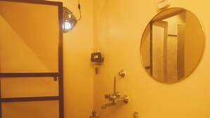 A bathroom with a sink, mirror, shower, and a trash bin. - Shades of Kashi with an artistic and cozy stays for couple and family. (varanasi)