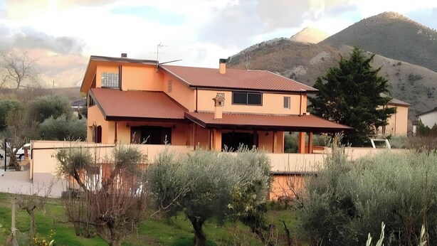 Uma casa de dois andares com telhado inclinado, garagem e vista para uma montanha.
