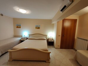 Een hotelkamer met een groot bed, twee nachtkastjes, een radiator en een houten deur.