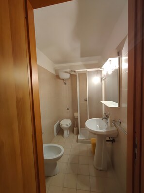 Een badkamer met toilet, bidet, wastafel en douche.
