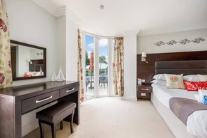 Ein Hotelzimmer mit Bett, Schreibtisch, Sitzbank, Spiegel und Blick ins Freie.