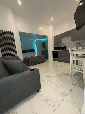 A modern kitchen with grey cabinets, a dining table, and a sofa. - Remarkable 8-bed House in Blackpool (Blackpool)