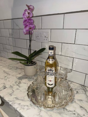 A bottle of Martini Bianco on a marble countertop with a glass tray and a potted plant. - Remarkable 8-bed House in Blackpool (Blackpool)