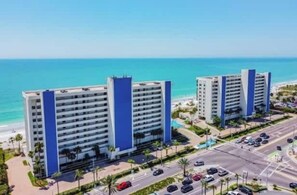 Ein Hochhaus-Hotel mit mehreren Etagen, einem Parkplatz und Blick auf den Strand.