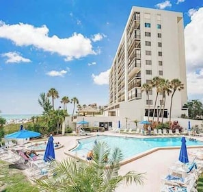 Ein Hotel mit Pool, Palmen und blauem Himmel.
