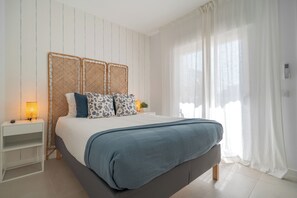 A bedroom with a bed, bedside table, and curtains. - 2-bedroom Apartment in Guargacho, Tenerife sur (Arona)